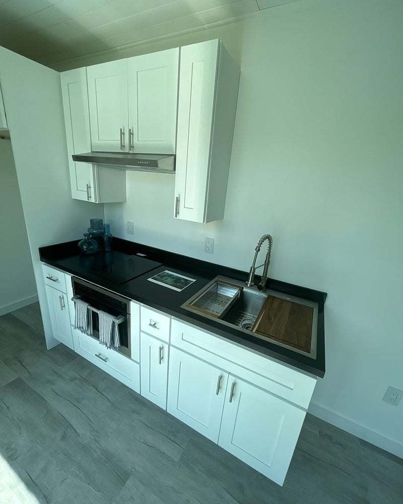 Modern kitchen with white cabinets, black countertop, and stainless steel sink.