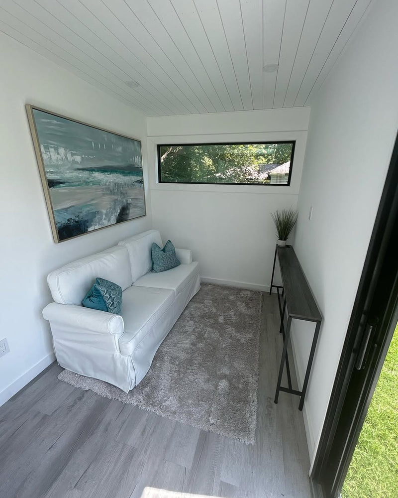 Modern interior with a white sofa, gray rug, and large window